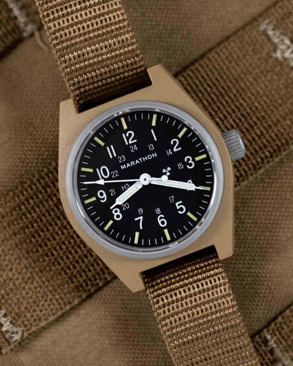 Marathon Desert Tan GPM on a ballistic nylon strap against tactical gear. Field Mechanical, Type II watch designed for rugged ground operations.