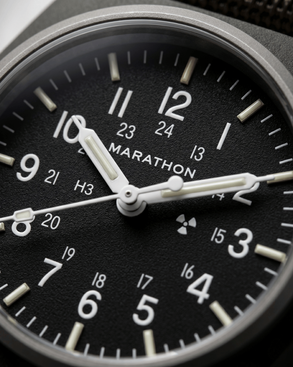 Close-up of the Marathon GPM Sage Green dial. Features Tritium gas tubes for visibility and a scratch-resistant sapphire crystal. Professional military watch.