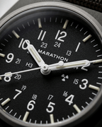 Close-up of the Marathon GPM Sage Green dial. Features Tritium gas tubes for visibility and a scratch-resistant sapphire crystal. Professional military watch.