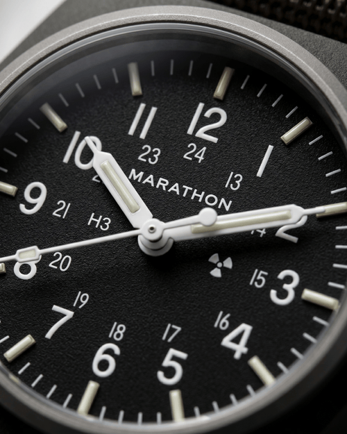 Close-up of the Marathon GPM Sage Green dial. Features Tritium gas tubes for visibility and a scratch-resistant sapphire crystal. Professional military watch.