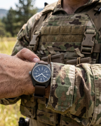 A tactical operator wearing the Marathon Sage Green GPM on a nylon strap. Built for ground operations and high-impact durability. Field Mechanical, Type II.