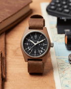 Marathon military watch on desk. Desert Tan GPQ-D style for professional watch collections.