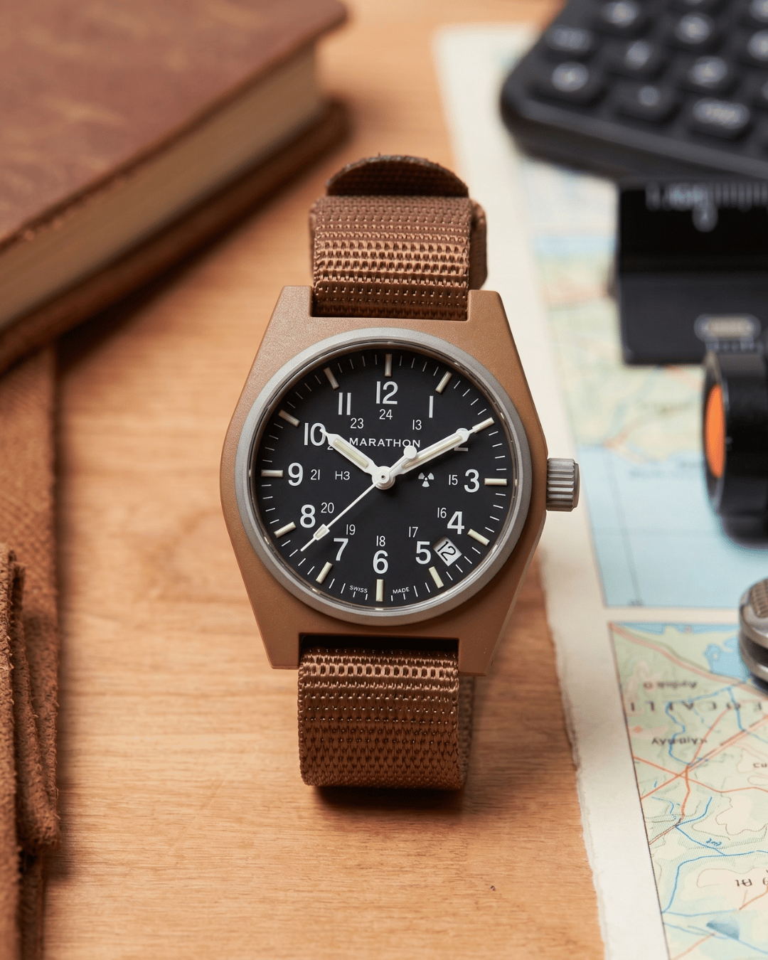 Marathon military watch on desk. Desert Tan GPQ-D style for professional watch collections.